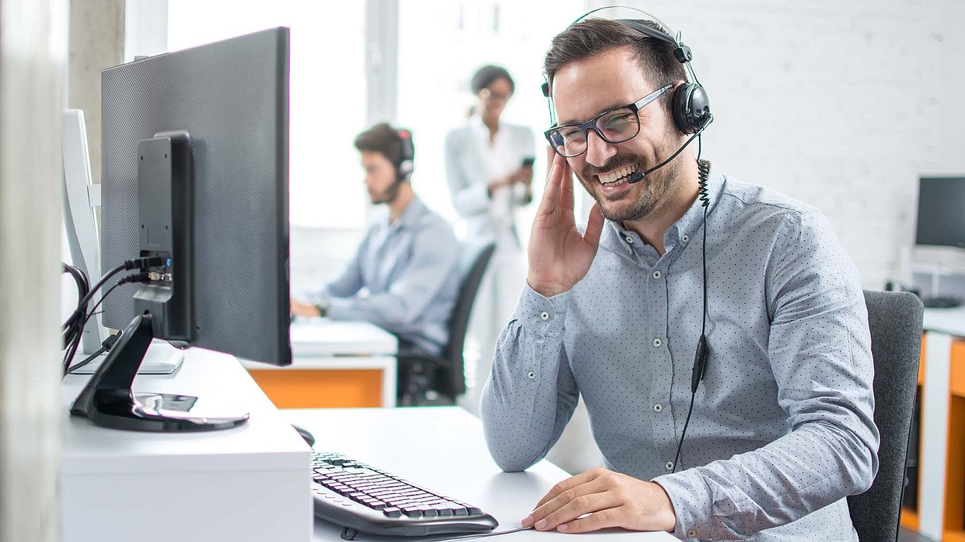 Cheerful technical support dispatcher talking with customer using headset in call center; Shutterstock ID 1061540957; Purchase Order: -